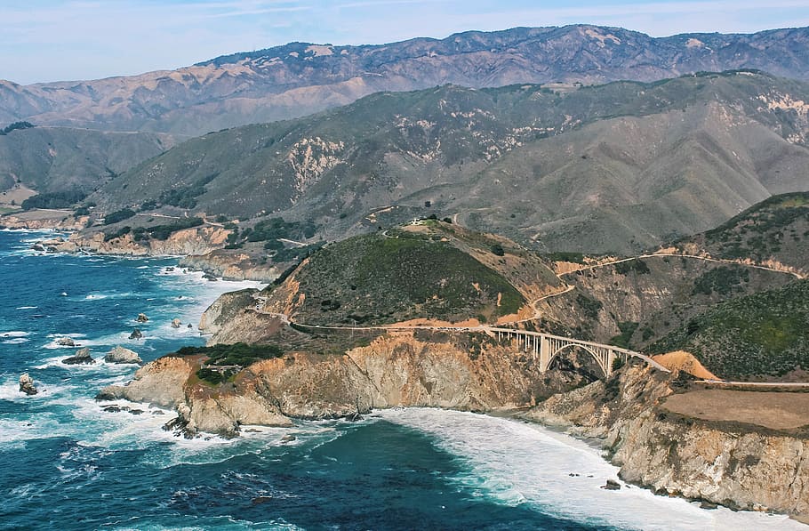 mountain near body of water during daytime, aerial photography of metal bridge connecting ridge near ocean during daytime HD wallpaper