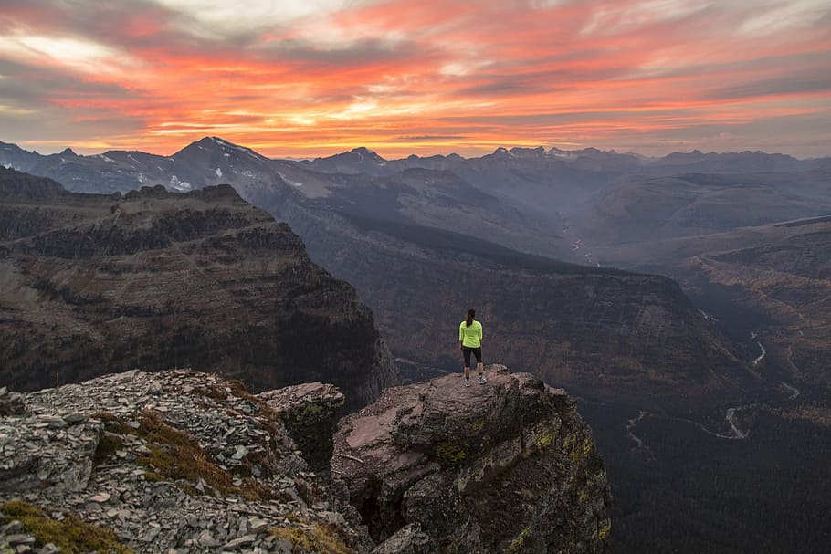 person wearing green standing on peak of mountain during golden hour HD wallpaper