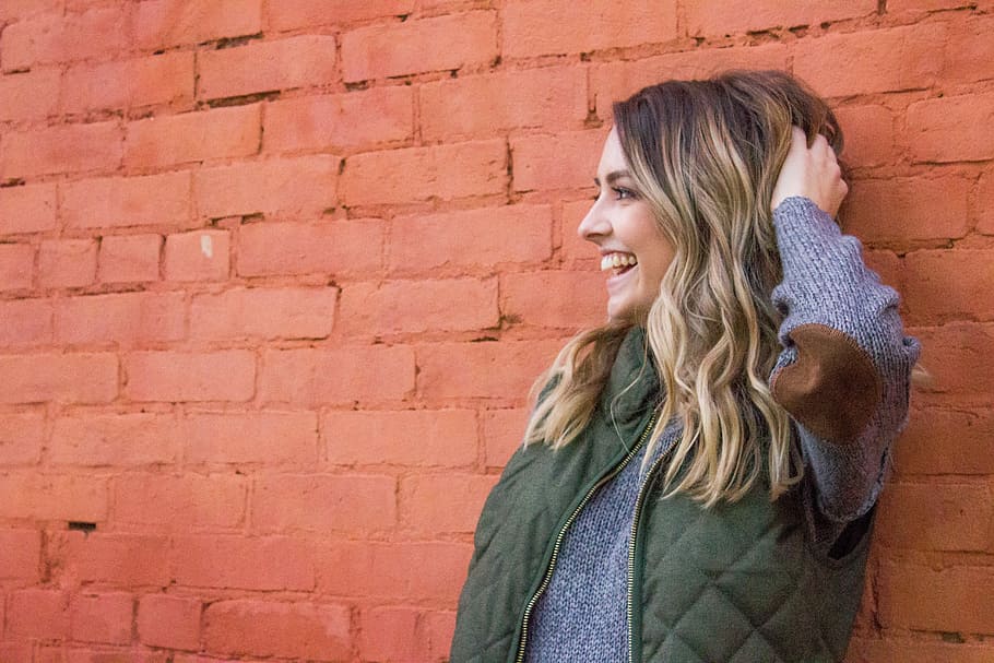 woman holding her her while leaning on red brick wall, woman holding her hair while leaning on red brick wall HD wallpaper