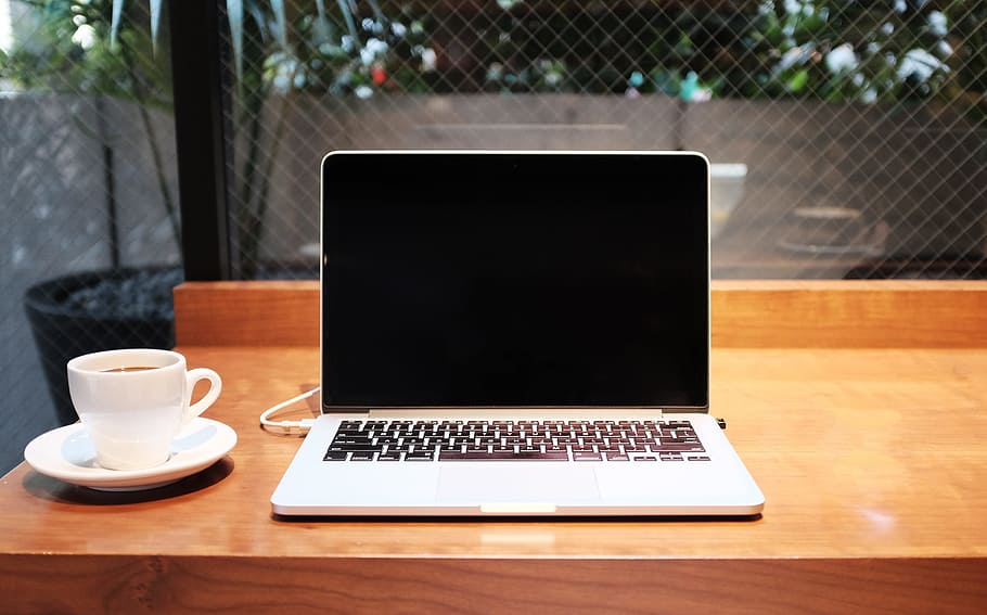 silver laptop computer beside ceramic teacup on wooden table HD wallpaper