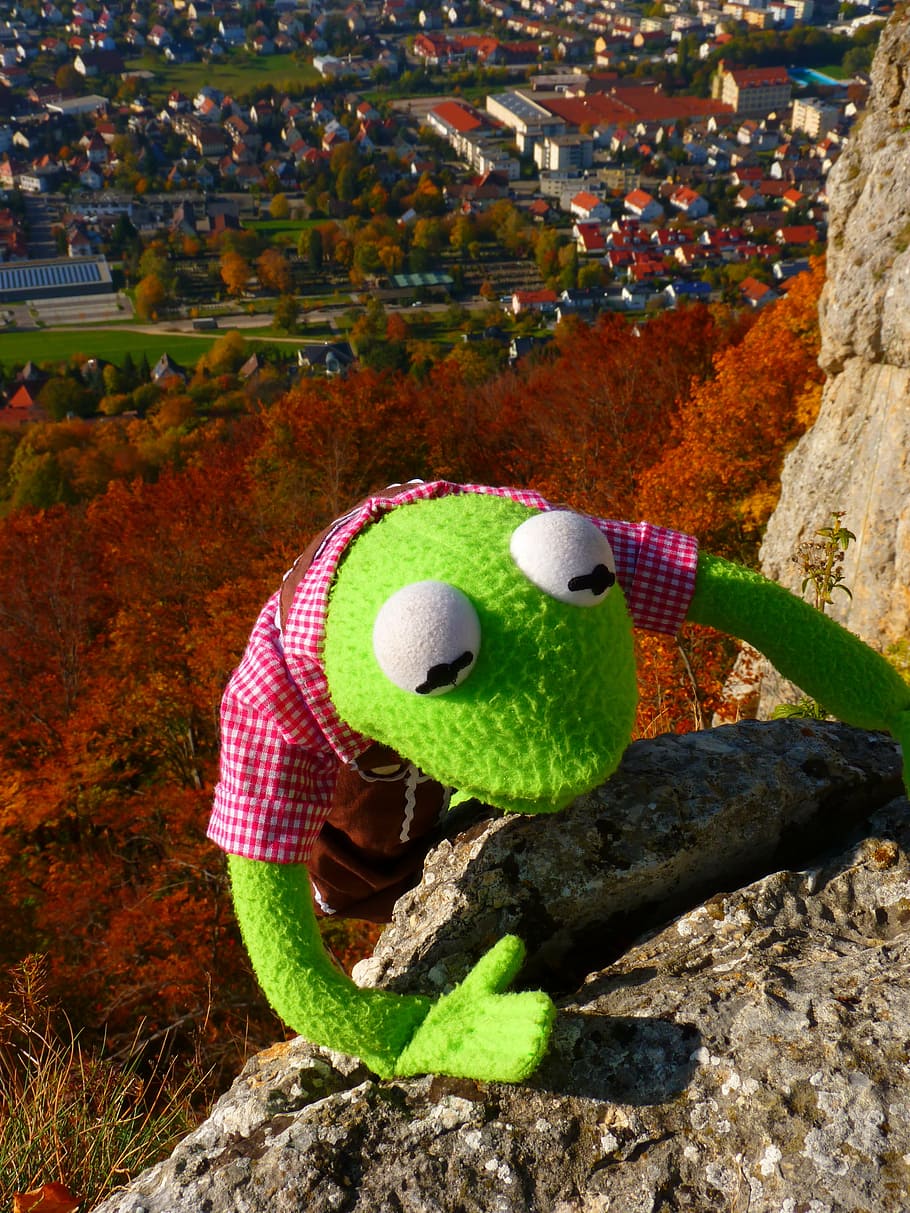 green frog plush toy climbing on brown stone cliff, rock, kermit HD wallpaper