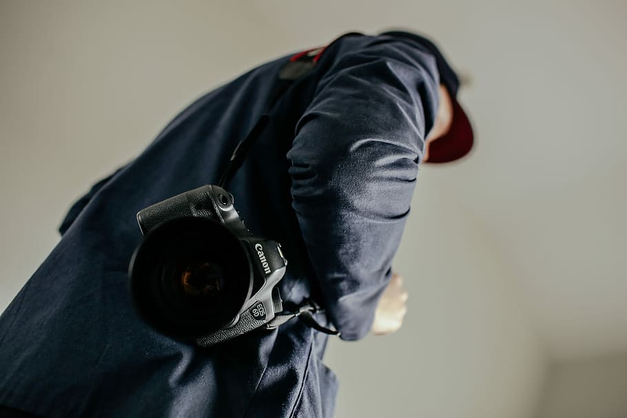 man carrying a black Canon DSLR camera, Canon DSLR camera on mans shoulder HD wallpaper