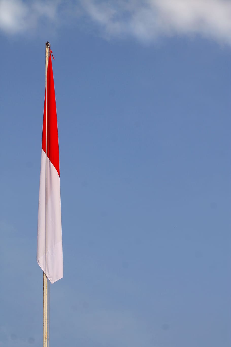 white and red flag mounted in pole under clear blue sky, Indonesia