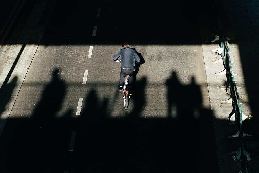 person riding bicycle on concrete road during daytime, dark HD wallpaper