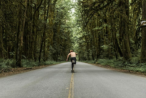 man playing skateboard on road between forest, skating, green HD wallpaper