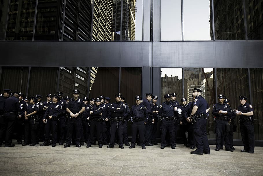 group of police standing near grey building, group of police officers standing near concrete building