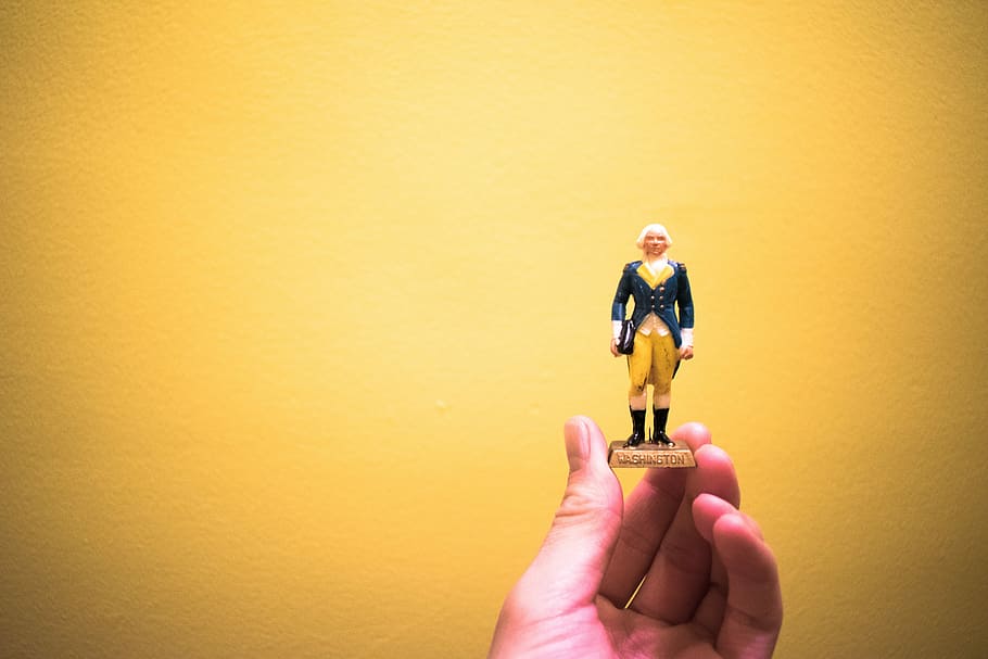 person holding man wearing black suit figurine, person holding man in black coat mini figure HD wallpaper