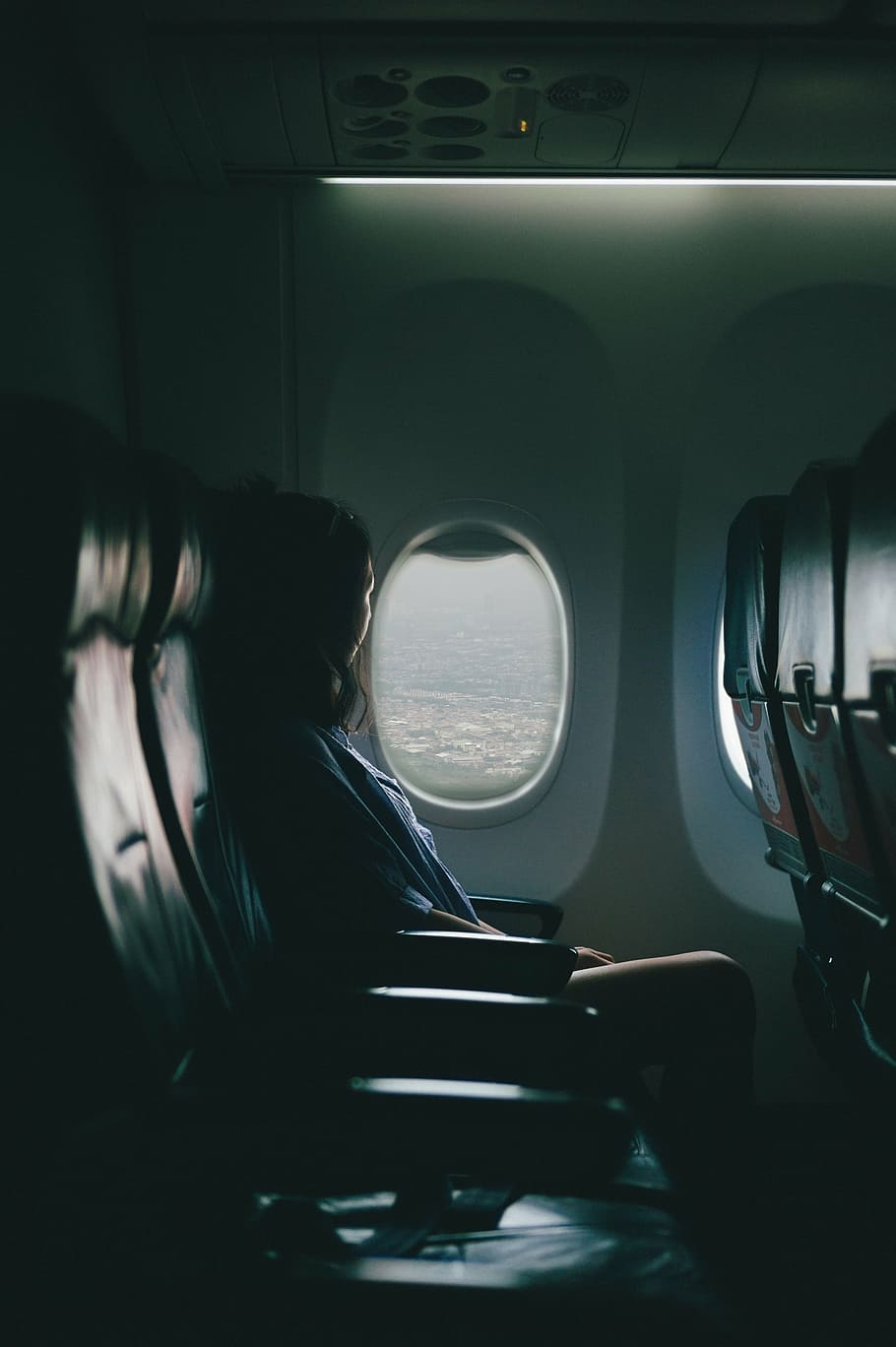 woman sitting inside airplane while looking outside, near, window