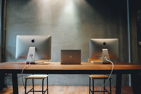 two silver iMac's and silver MacBook in between on brown table HD wallpaper