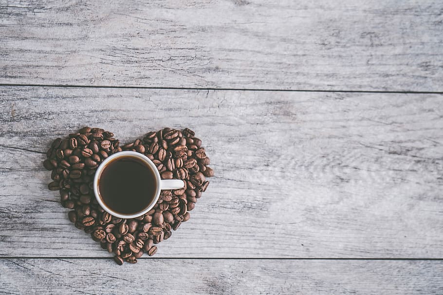 coffee filled white ceramic mug beside brown coffee beans on beige wooden surface, white ceramic coffee mug filled with black liquid HD wallpaper