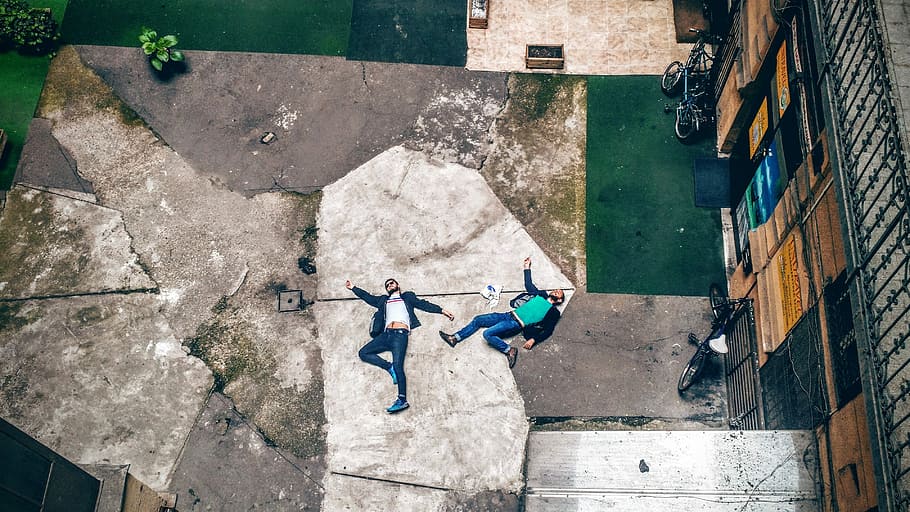 aerial view of two men lying on concrete pavement, men lying on concrete pavement HD wallpaper