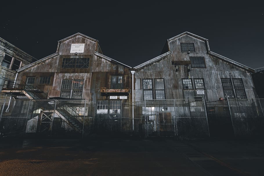 two barnyard at night, two rusted gray wooden houses under gray sky at night time