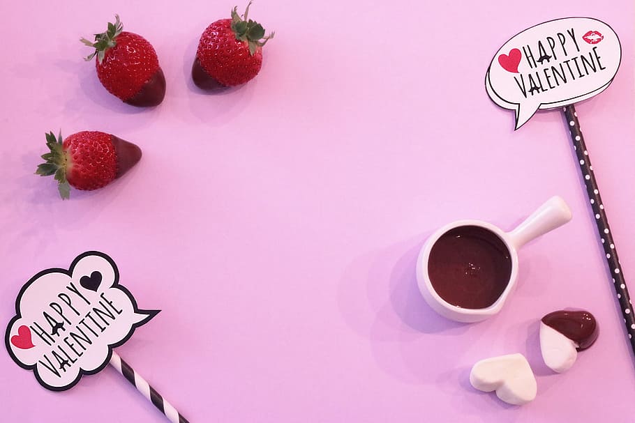 three red strawberries, white ceramic cup, and white heart mallows on pink surface HD wallpaper