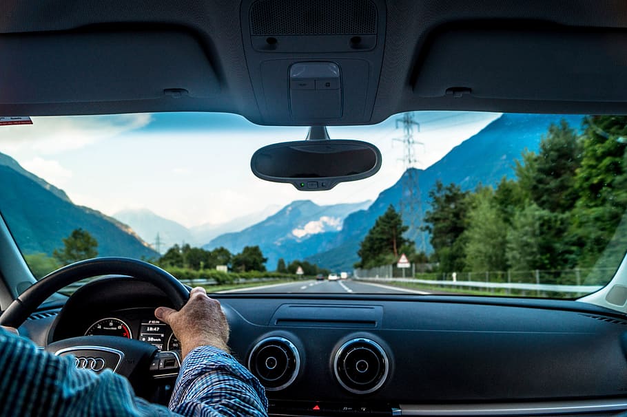 Man driving a car on road in the mountains of Switzerland, people