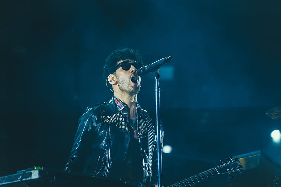band vocalist, man singing holding guitar inside stage, black leather jacket HD wallpaper