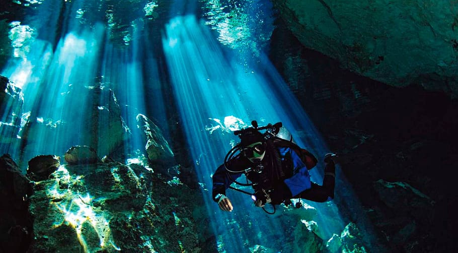 person diving underwater with sunlight, cenote, yucatan, sea