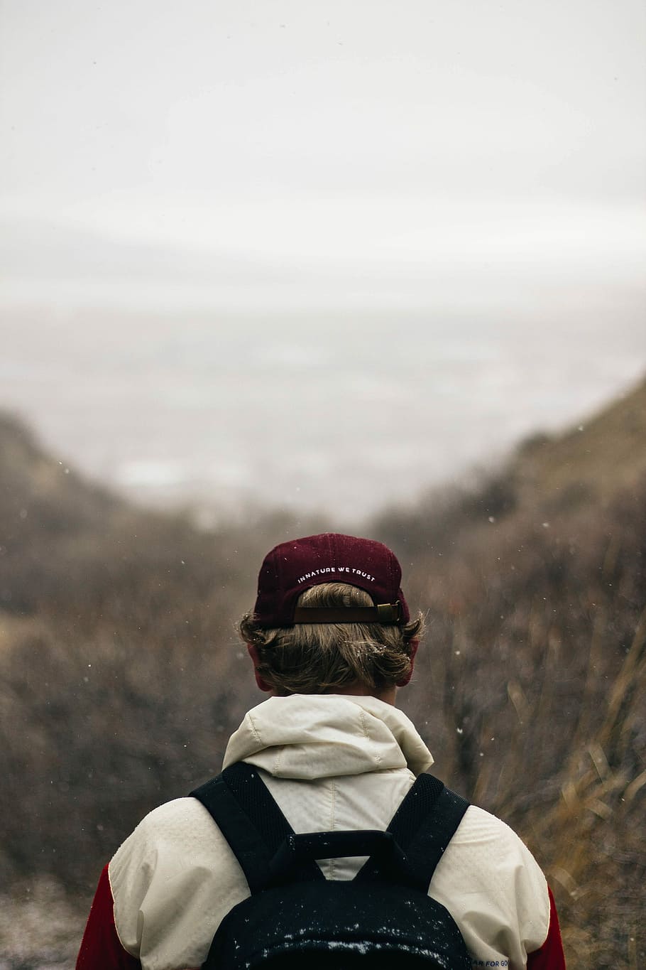 person wearing red cap and carrying black backpack, man walking on field HD wallpaper