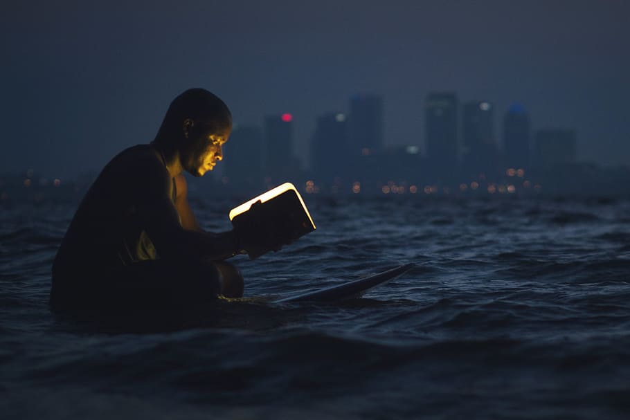 Man reading a book in the ocean at night, people, books, coast