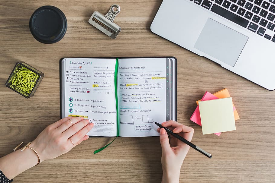 woman writing on a planner beside silver MacBook, laptop, apple HD wallpaper