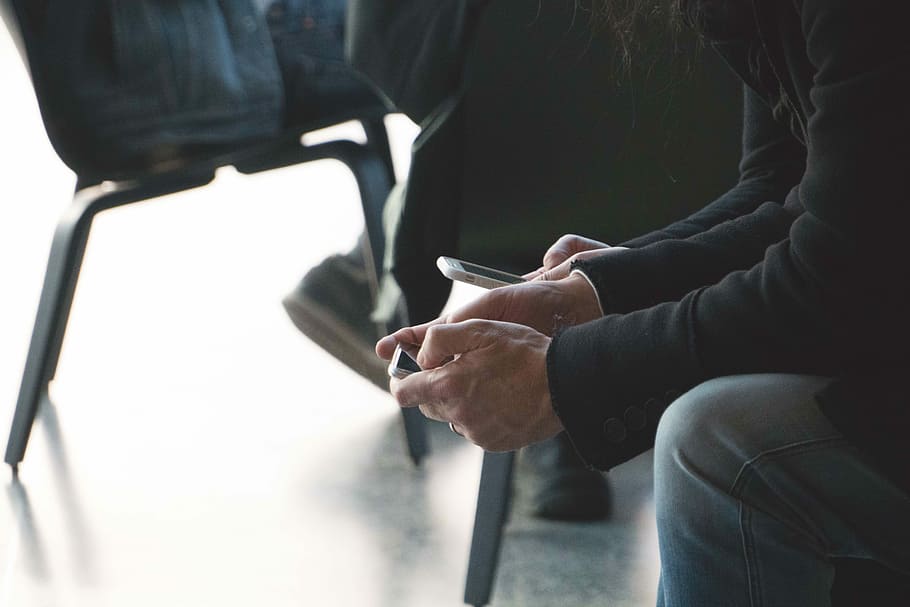 person sitting on chair while using smartphone close-up photo, person using mobile phone HD wallpaper