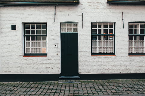 photo of white concrete house, closed door and window concrete house at daytime HD wallpaper