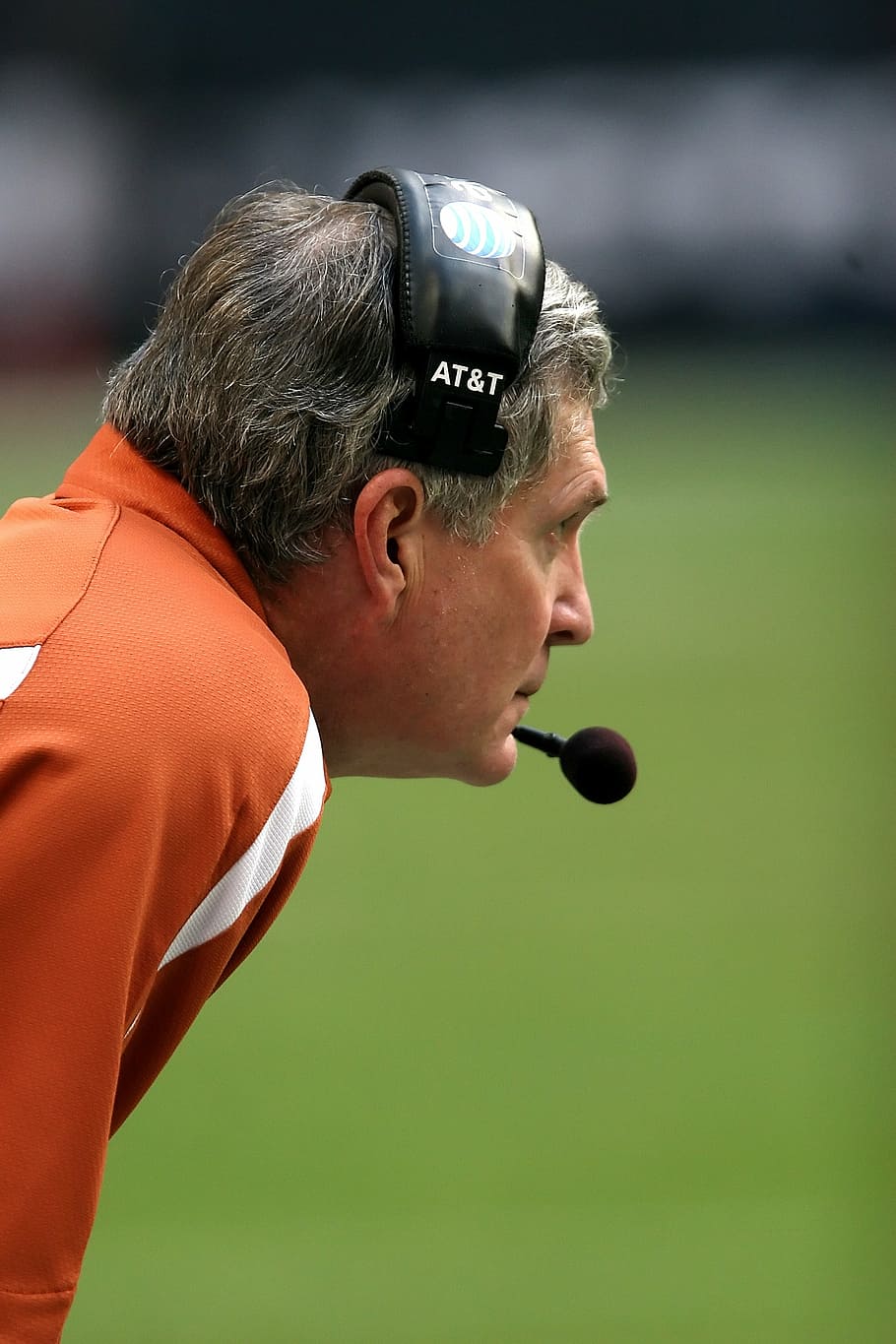 man in orange and white polo shirt wearing black and white AT&T headset