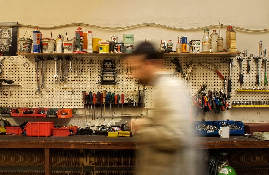 person wearing gray long-sleeved top beside workbench, workshop HD wallpaper