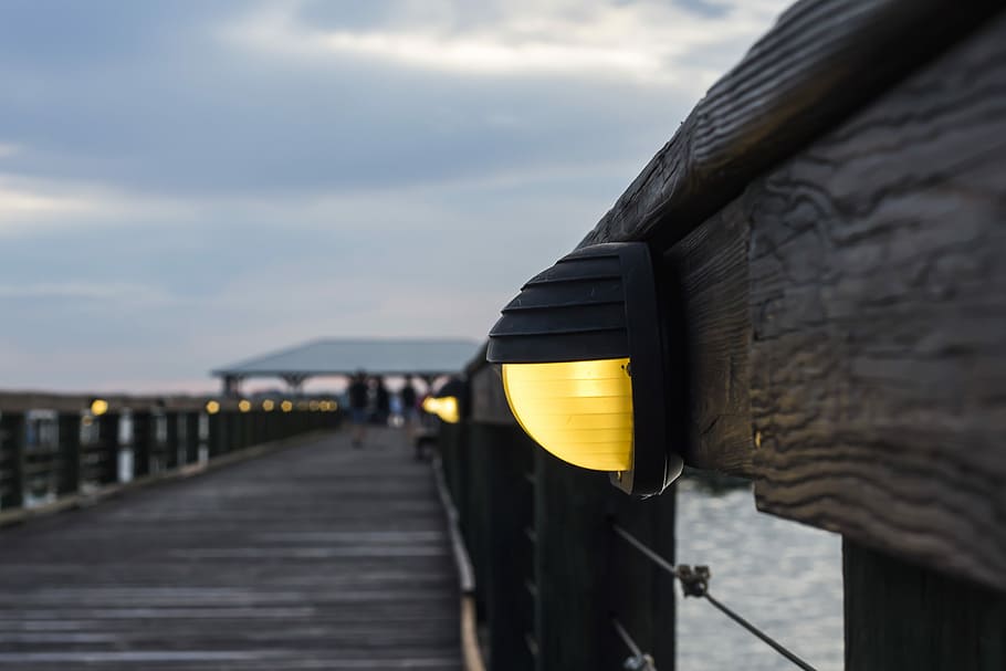wooden dock with lights turned on at night, focus photography of dock sidewalk post lamp HD wallpaper