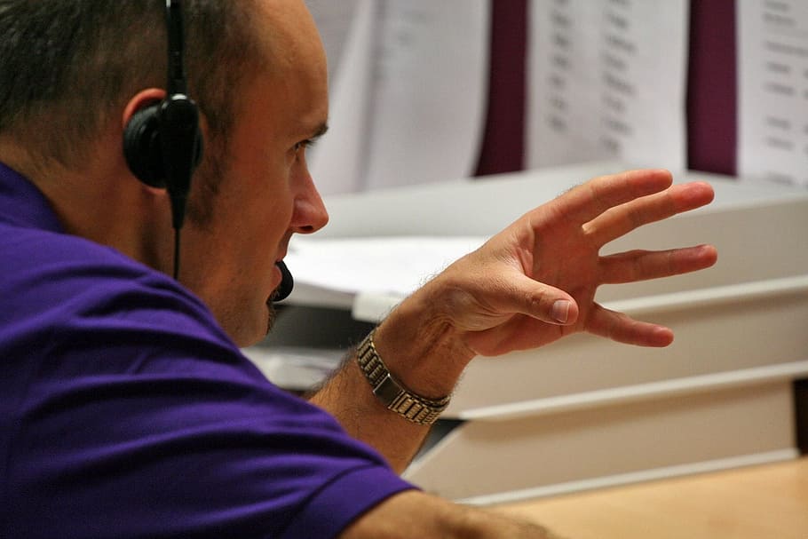 man in purple top doing hand gesture, phone, talking about, work