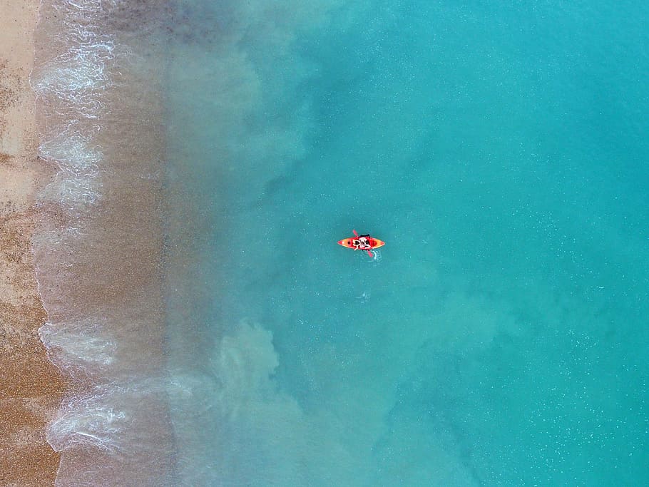 person kayaking on body of water, person riding kayak near brown sea shore HD wallpaper