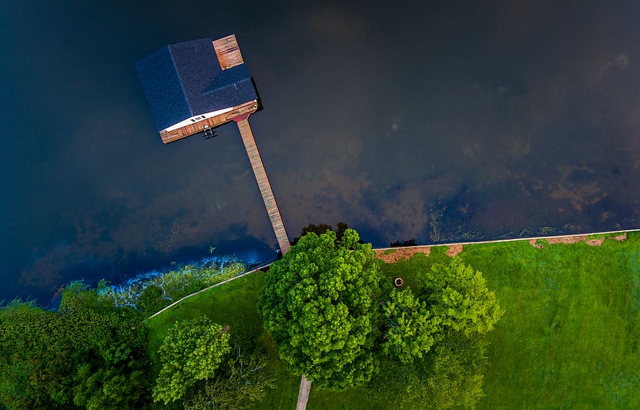 blue wooden house on body of water near green trees, house off the coast with wooden footbridge aerial photography HD wallpaper