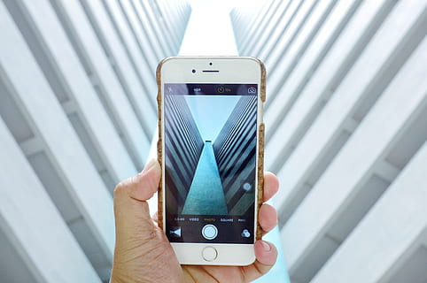 A photographer takes a photo of a building with his iPhone mobile smartphone camera HD wallpaper