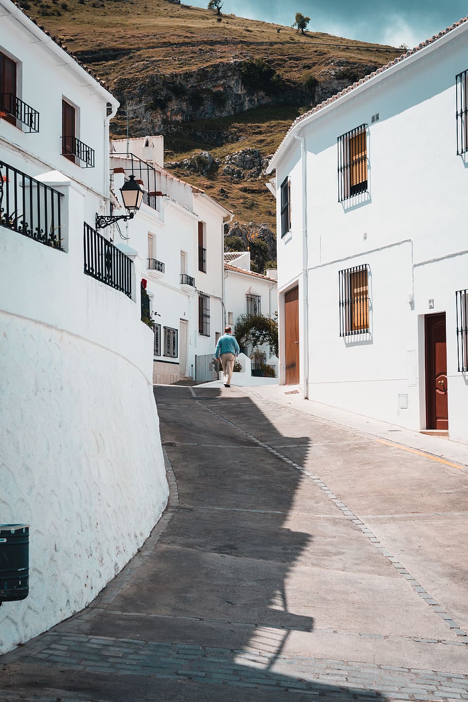 man walking near houses, man walking between concrete building during daytime HD wallpaper