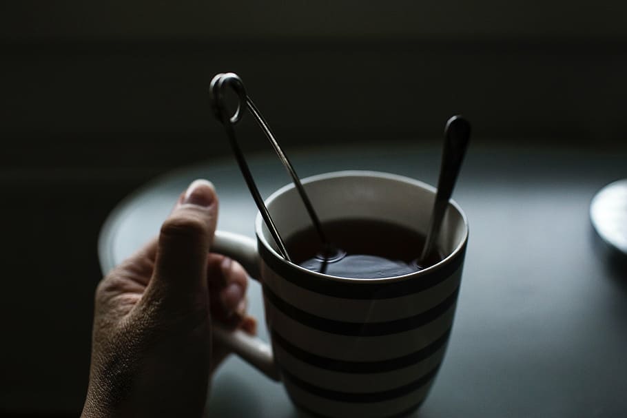 person holding mug with safety pin, dark, coffee, drink, table