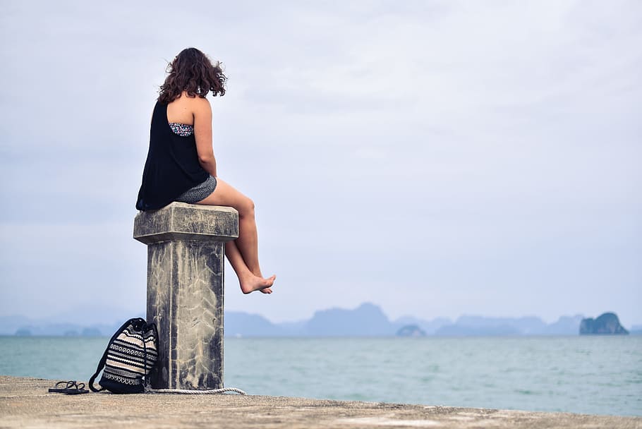 Woman in Black Shirt Sitting Near Body of Water during Daytime HD wallpaper