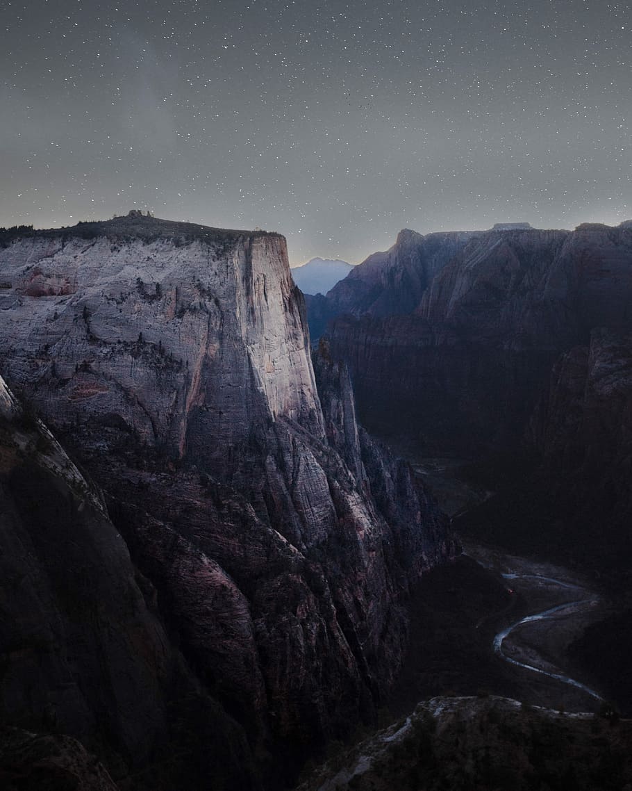 brown rocky cliff during nighttime, gray mountain near river under starry sky HD wallpaper