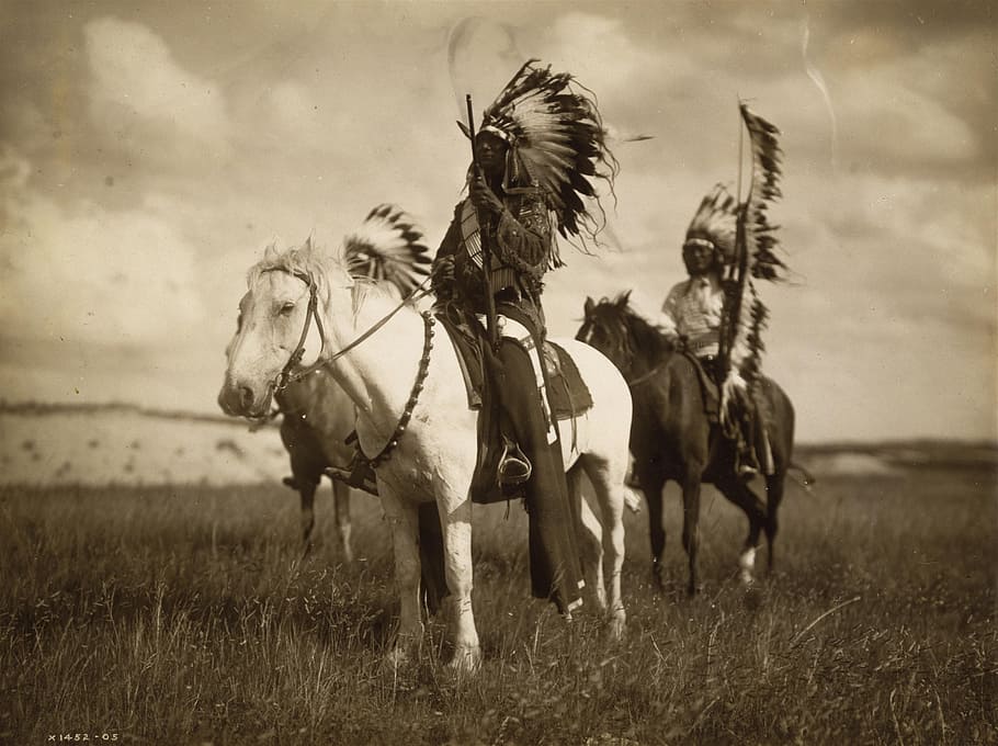 three native Americans riding on the horse on the green grass field photo