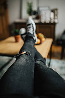 Woman in ripped jeans and black sneakers with a silver laptop on a wooden table HD wallpaper