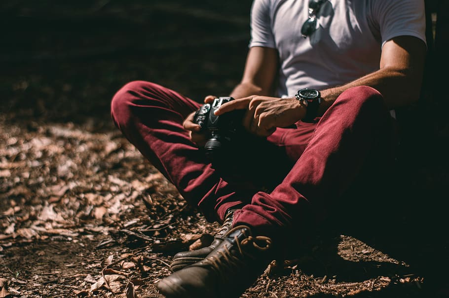 man sitting on soil white holding camera, man holding camera HD wallpaper