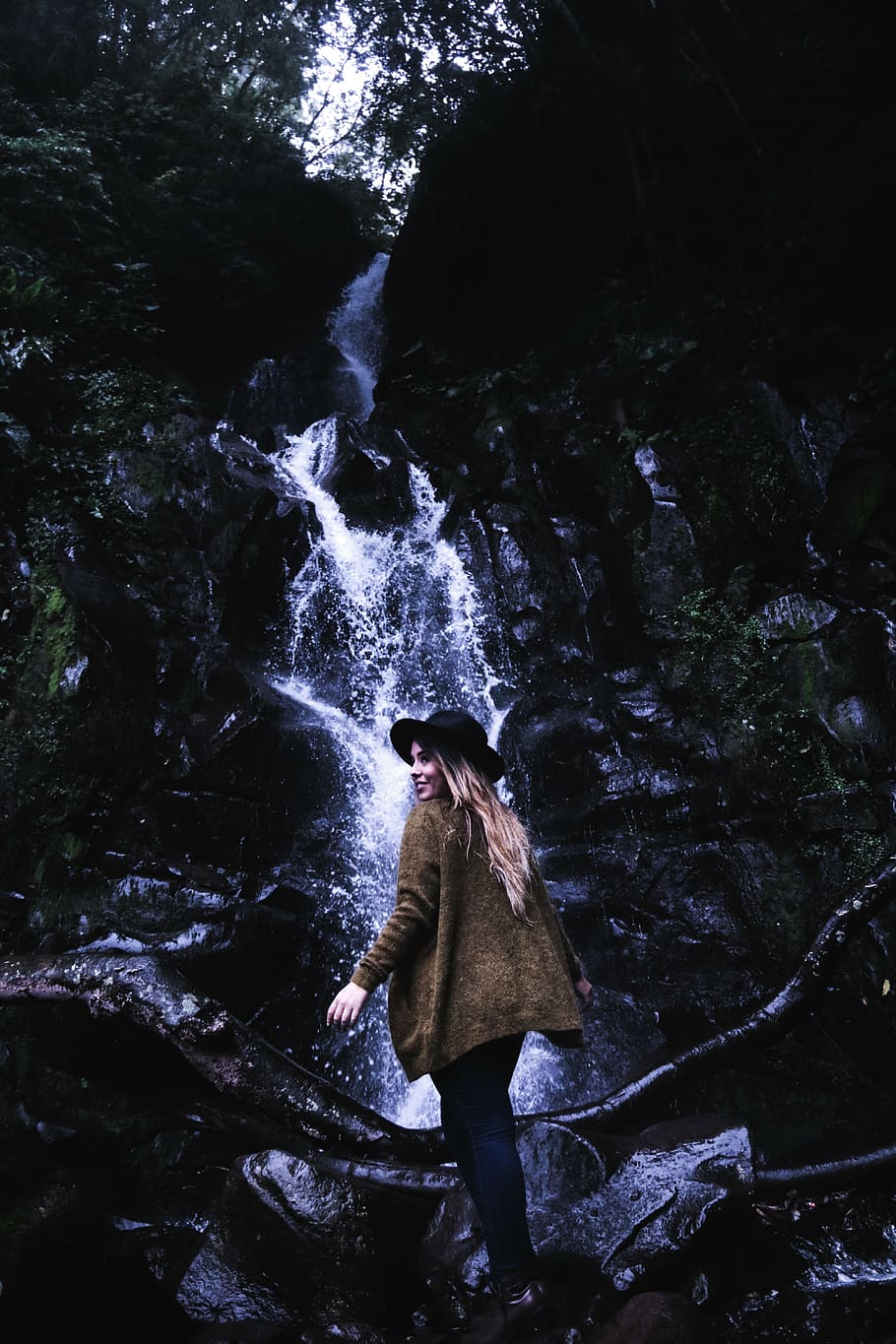 woman in brown jacket and black hat near waterfalls, standing HD wallpaper