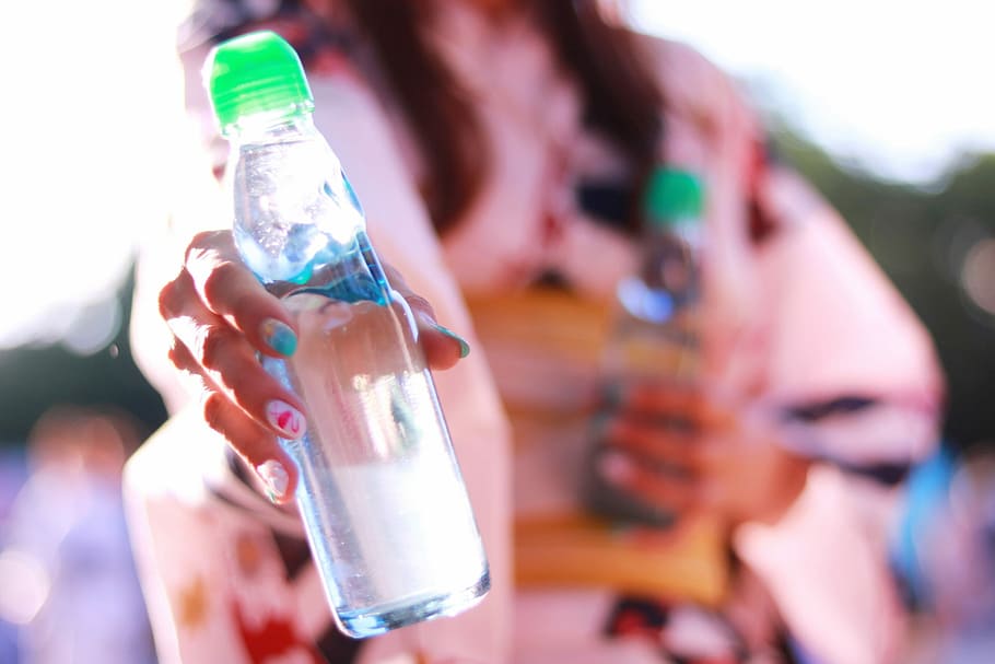 selective focus photography of woman holding clear glass water bottle HD wallpaper
