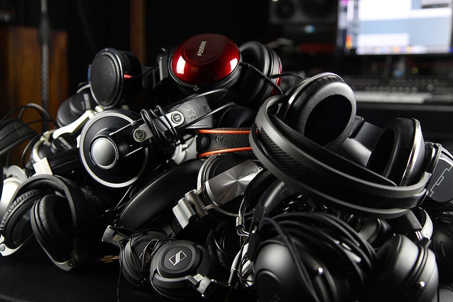 black Sennheiser corded headphones lot on black surface, pile