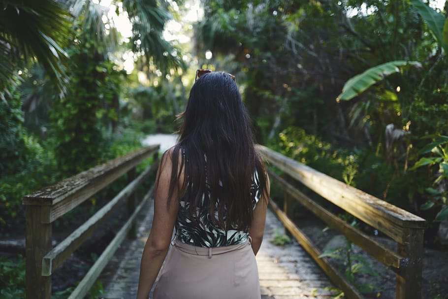 woman wearing black and brown sleeveless dress walking on brown wooden footbridge during daytime HD wallpaper