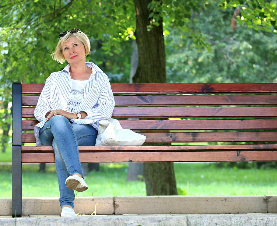 Thinking Woman in White Jacket and White Scoop Neck Shirt Blue Denim Jeans Sitting on Brown Wooden Bench Beside Green Trees during Daytime, HD wallpaper