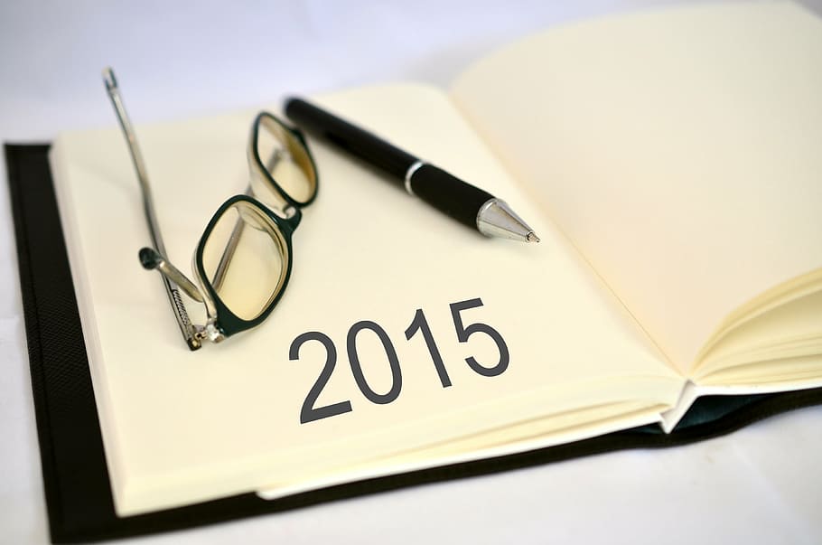 2015 text on white book page beside eyeglasses and pen, dates HD wallpaper