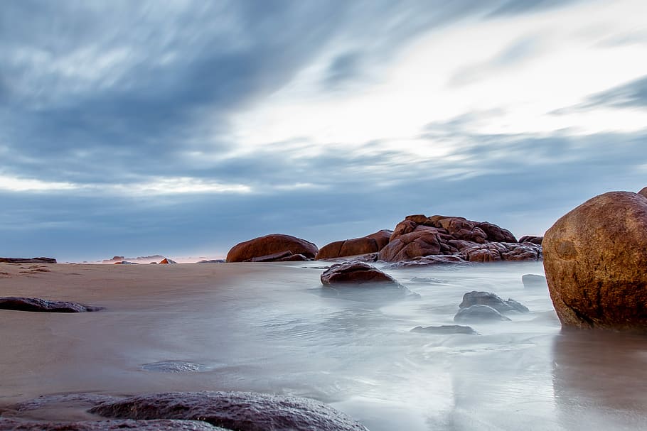 rock formations in body of water, rocks on beach under cloudy blue sky HD wallpaper