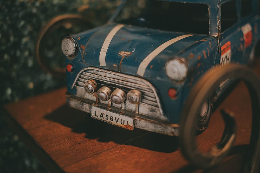 blue vintage car scale model, blue and gray die-cast metal car toy on brown wooden surface