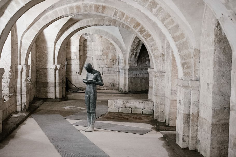 Anthony Gormely sculpture in Winchester Cathedral, black concrete statue on gray hallway HD wallpaper