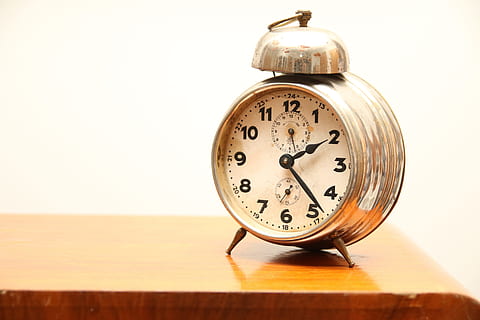 round gold-colored framed analog alarm clock on brown wooden surface HD wallpaper