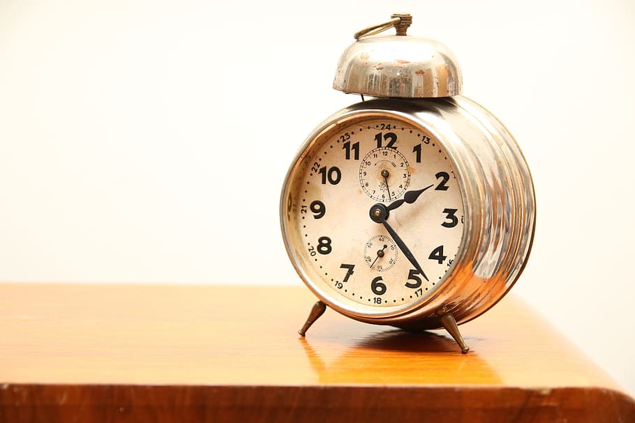 round gold-colored framed analog alarm clock on brown wooden surface HD wallpaper